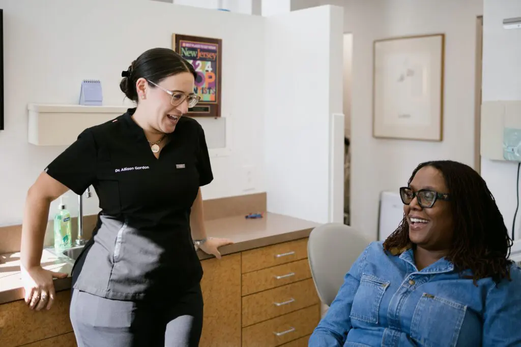 a woman standing next to a woman sitting in a chair