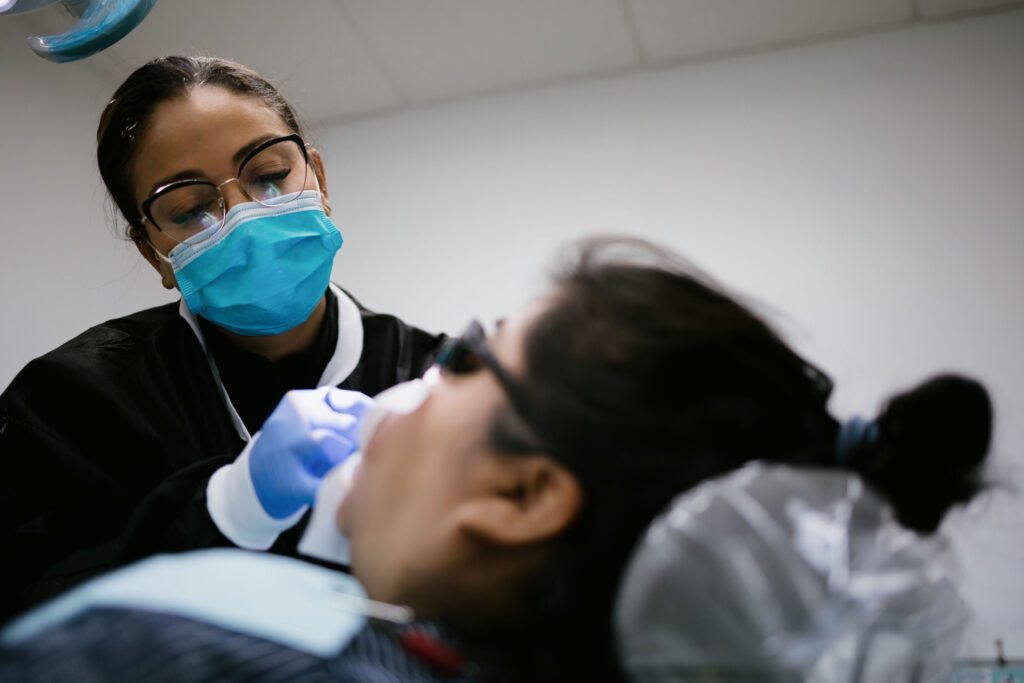 a woman in a mask and gloves getting a dental treatment