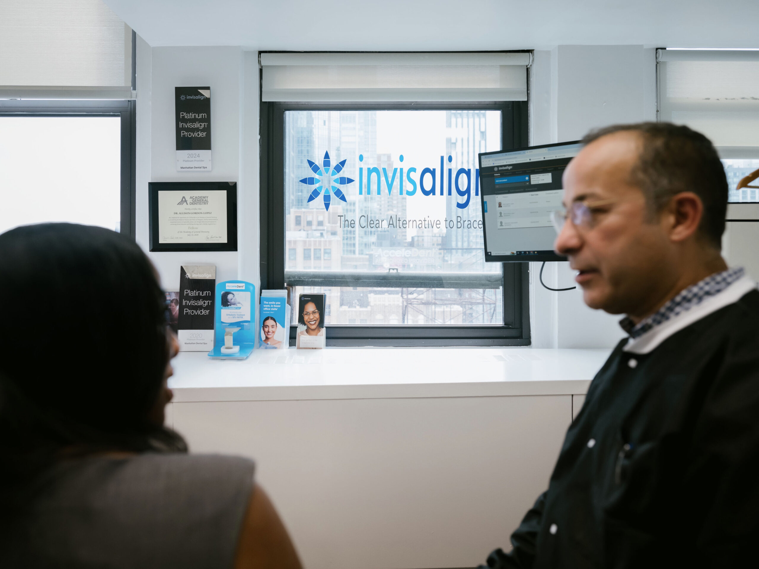 a man and woman sitting in front of a window with the invisalign logo