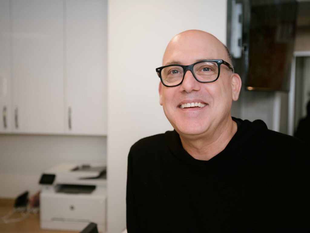 a man wearing glasses and smiling